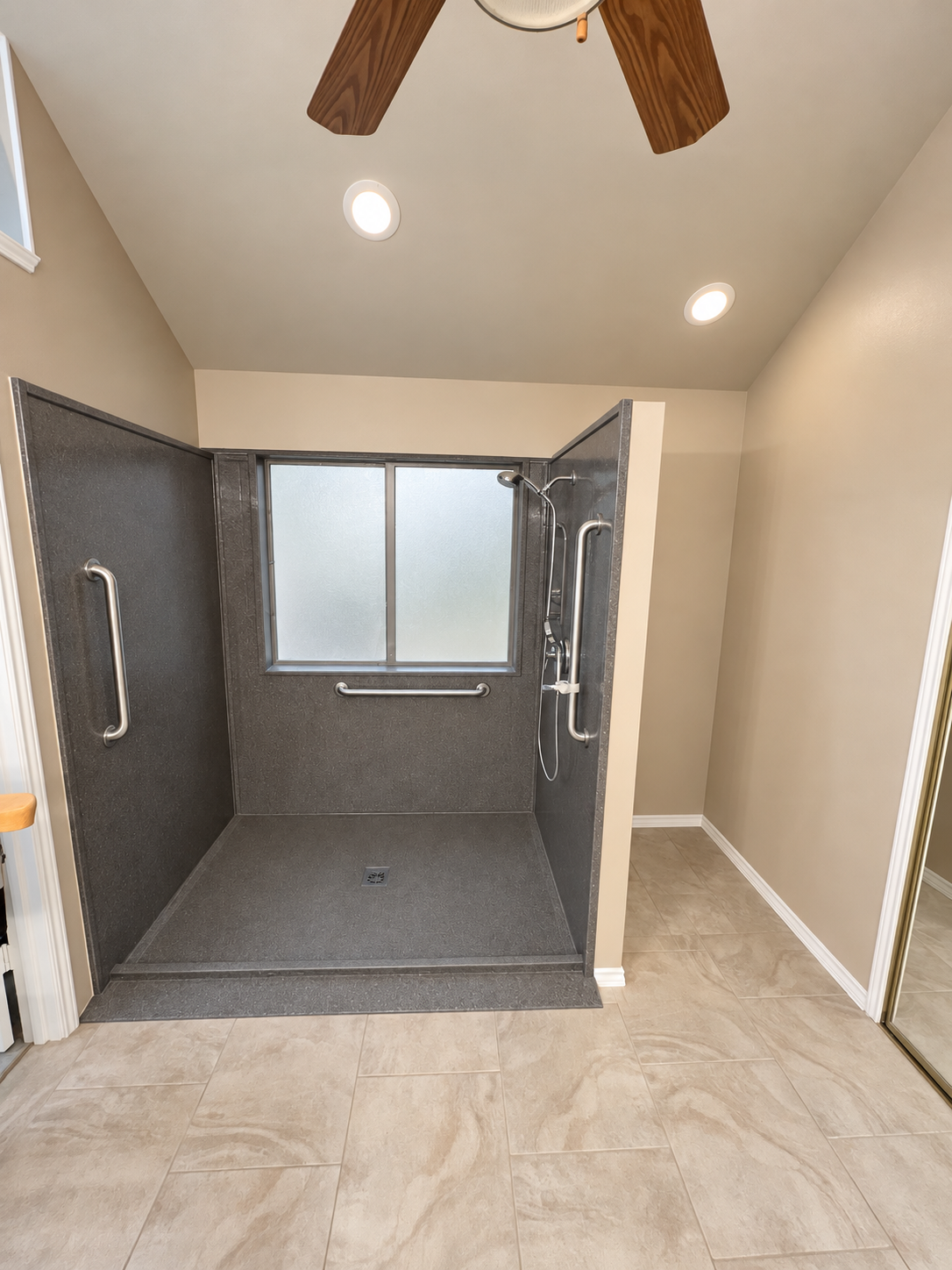 AccessAbility gray shower with a low entry, grab bars, and handheld showerhead